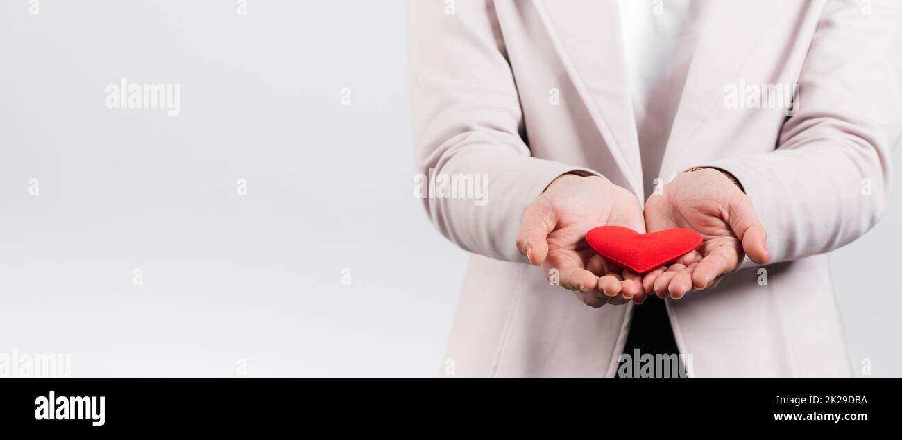 Femme souriante confiante montrant le cœur rouge avec sa main paume isolé fond blanc Banque D'Images