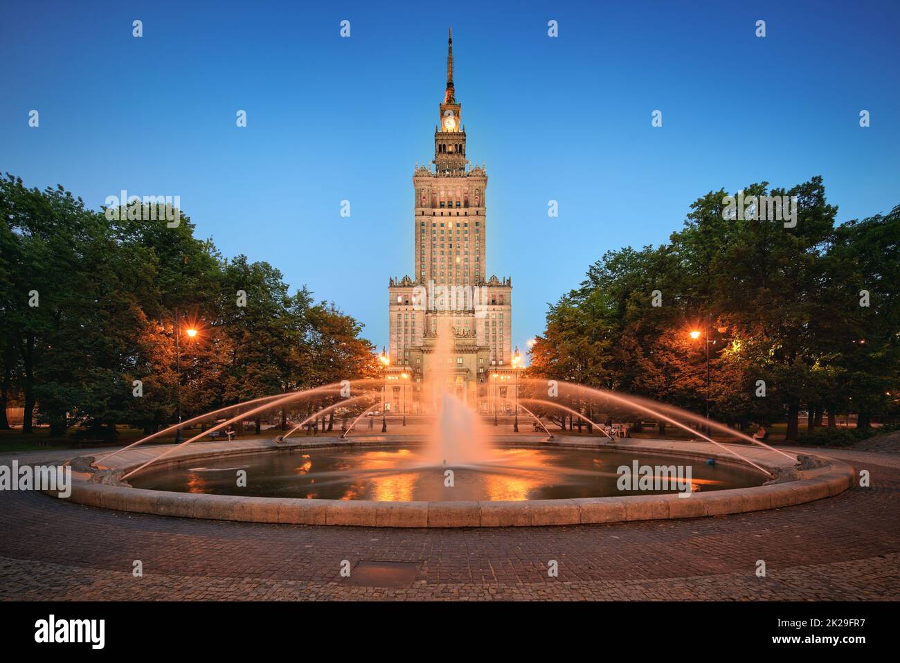 Varsovie la fontaine et le Palais de la Culture et de la Science en soirée Banque D'Images