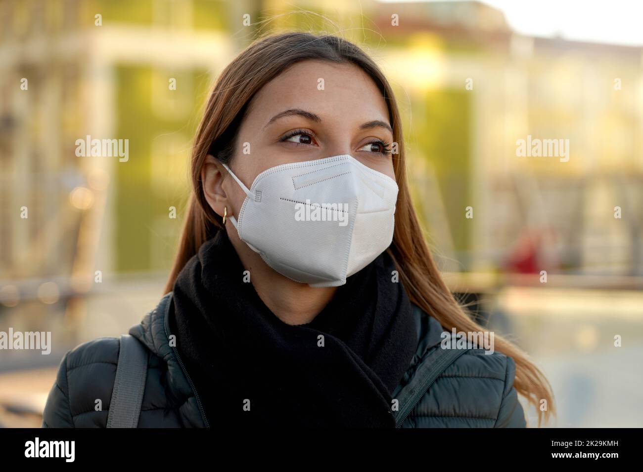 Belle femme pleine d'espoir portant un masque protecteur de KN95 FFP2 dans la rue de la ville au coucher du soleil Banque D'Images