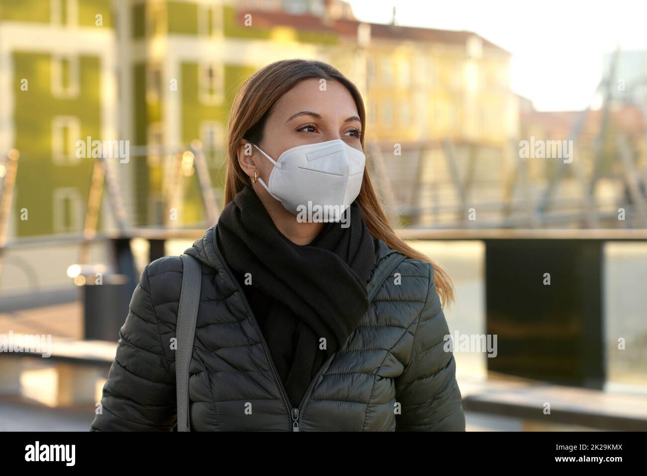 Belle décontractée jeune femme portant un masque de protection KN95 FFP2 marchant dans la rue de la ville au coucher du soleil Banque D'Images