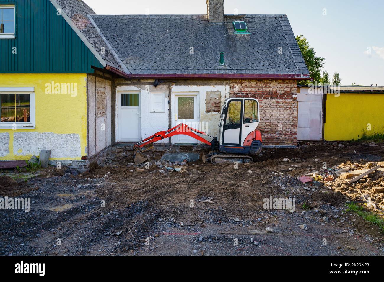 La maison familiale est en cours de rénovation avec l'aide d'une pelle hydraulique. Creuser la brique et la fondation en béton. Banque D'Images