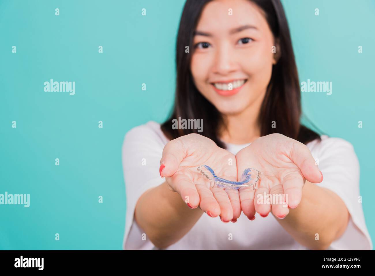 femme souriante tenant des pièces de retenue orthodontiques en silicone pour les dents sur la paume de la main Banque D'Images