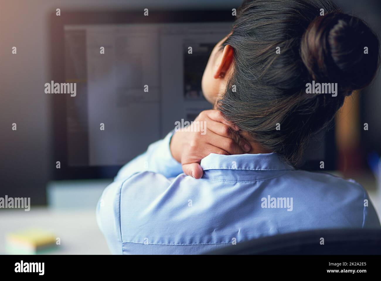 Ressentir la tension. Vue arrière d'une femme d'affaires souffrant de douleurs au cou au bureau. Banque D'Images