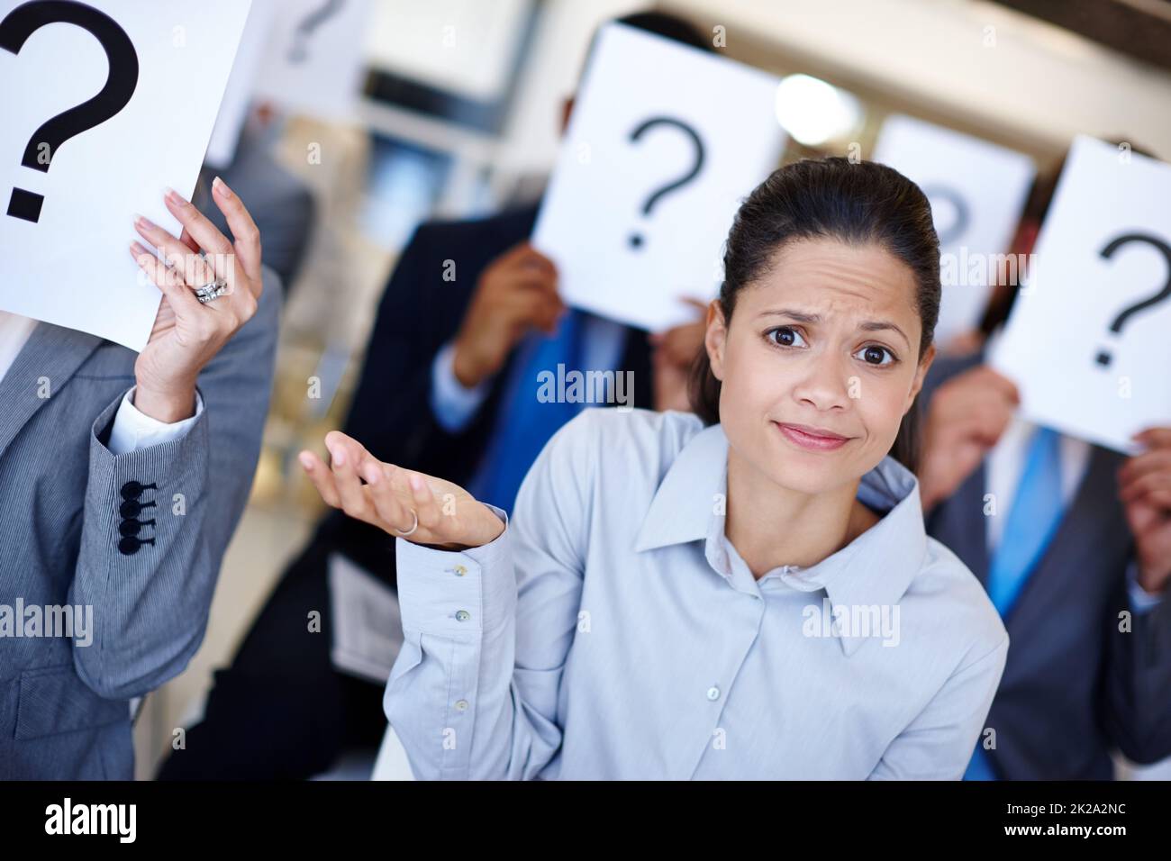 Je ne sais pas ce qui se passe. Photo d'un groupe d'hommes d'affaires qui tient des affiches avec des points d'interrogation lors d'une présentation de travail tandis que leur collègue semble confus. Banque D'Images