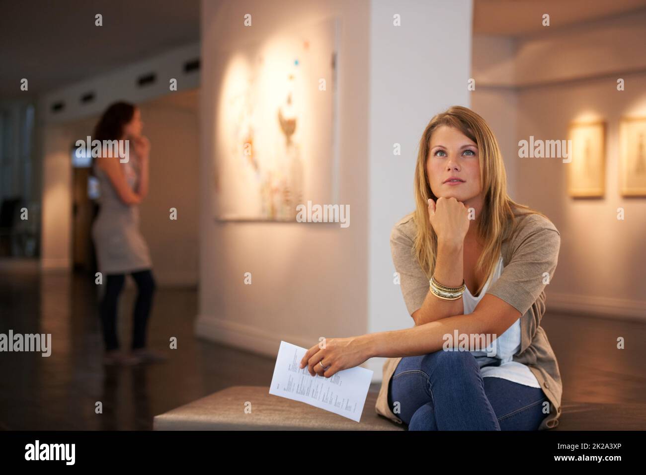 Réfléchir aux thèmes des peintures. Deux jeunes amis qui regardent des peintures tout en assistant à une exposition. Banque D'Images