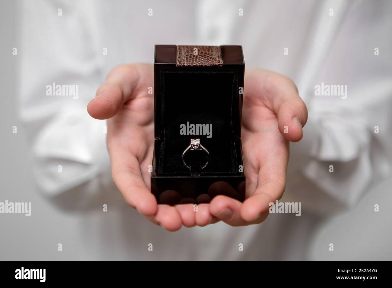 Un jeune homme tient dans ses mains une boîte à bijoux avec un anneau de diamant à l'intérieur Banque D'Images