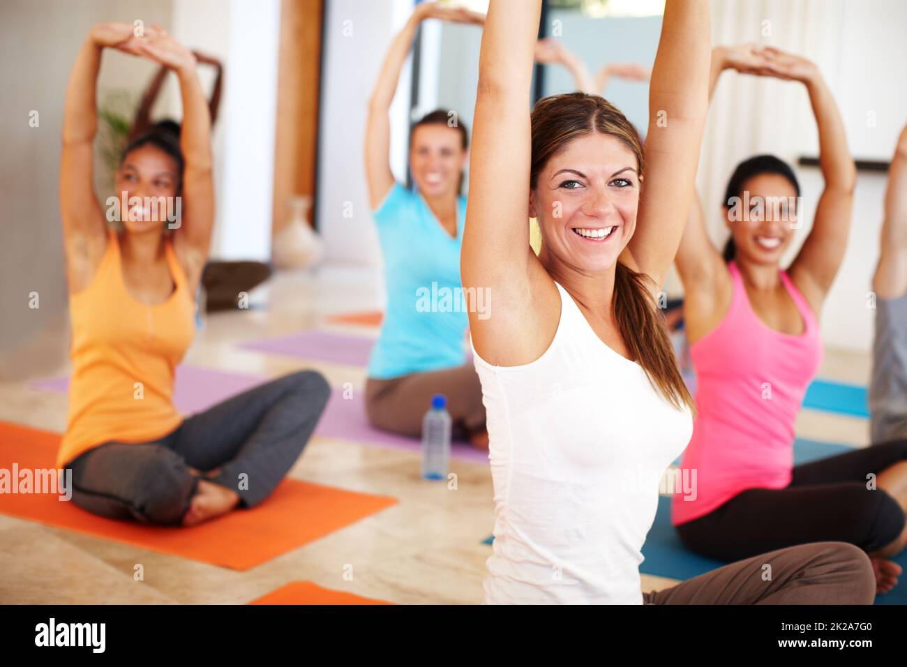 Rassembler le corps et l'esprit. Un groupe de personnes s'étendant vers le haut en cours de yoga. Banque D'Images