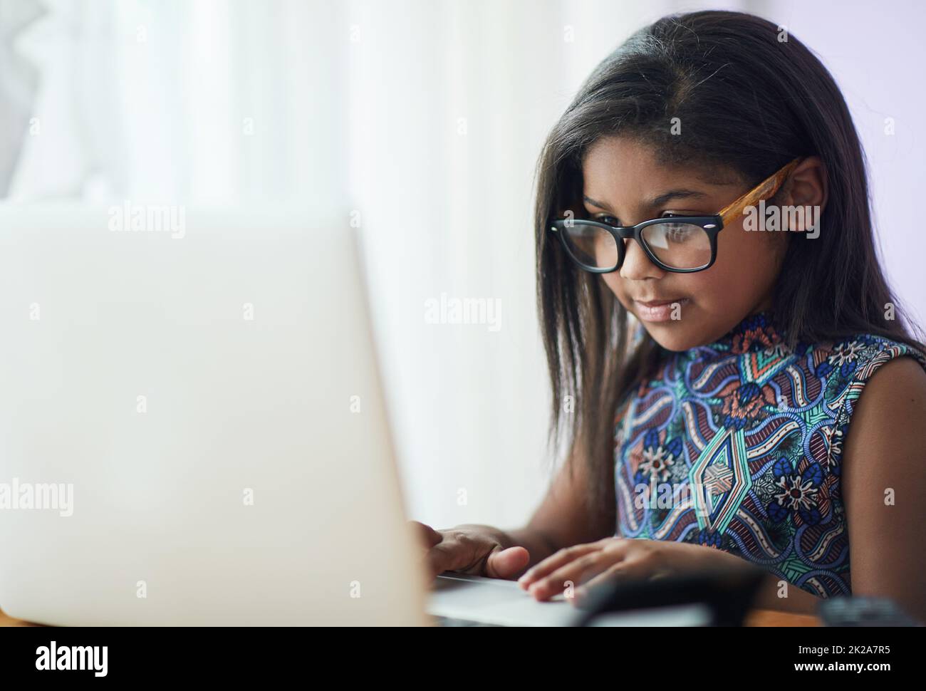 Pourquoi payer l'affranchissement quand vous pouvez envoyer un e-mail à granny à la place. Photo d'une petite fille mignonne utilisant un ordinateur portable dans sa chambre à la maison. Banque D'Images