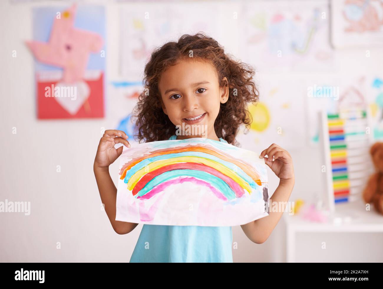 Vous n'aimez pas les couleurs. Photo d'une petite fille tenant une photo qu'elle peint d'un arc-en-ciel. Banque D'Images