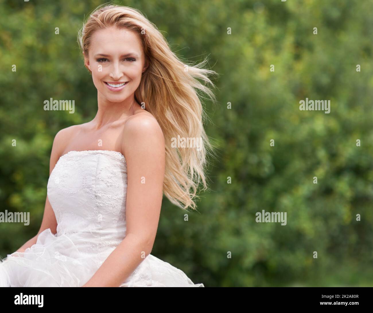 Magnifique le grand jour. Une jeune mariée magnifique souriant et regardant étourdissante dans sa robe de mariage aux côtés de l'espace d'imitation. Banque D'Images