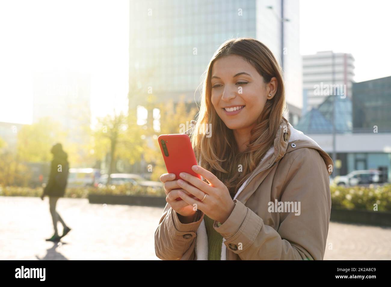 Portrait d'une fille à l'extérieur en utilisant un smartphone portant un manteau d'hiver regardant la vidéo en streaming Banque D'Images