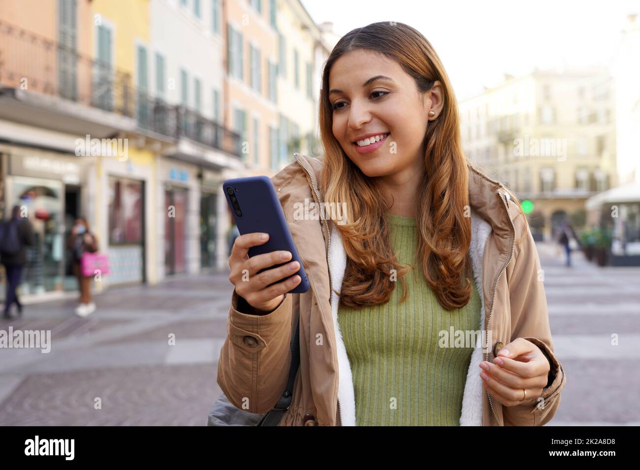 Portrait d'une fille en plein air avec application de chat sur un smartphone dans une zone piétonne Banque D'Images