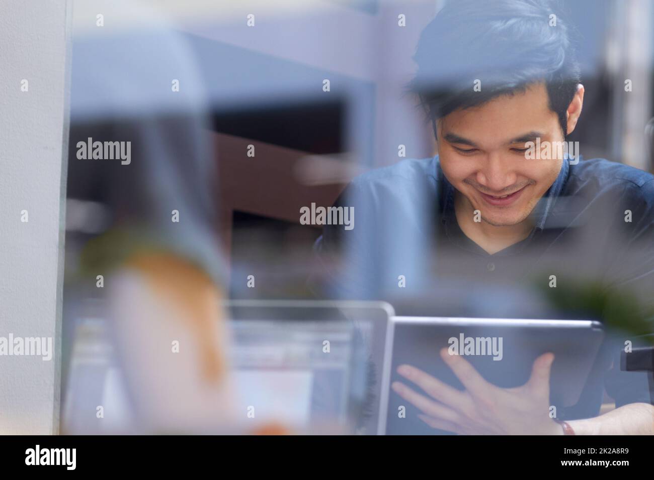 Détente dans le café Internet. Homme asiatique souriant utilisant une tablette numérique à l'intérieur. Banque D'Images