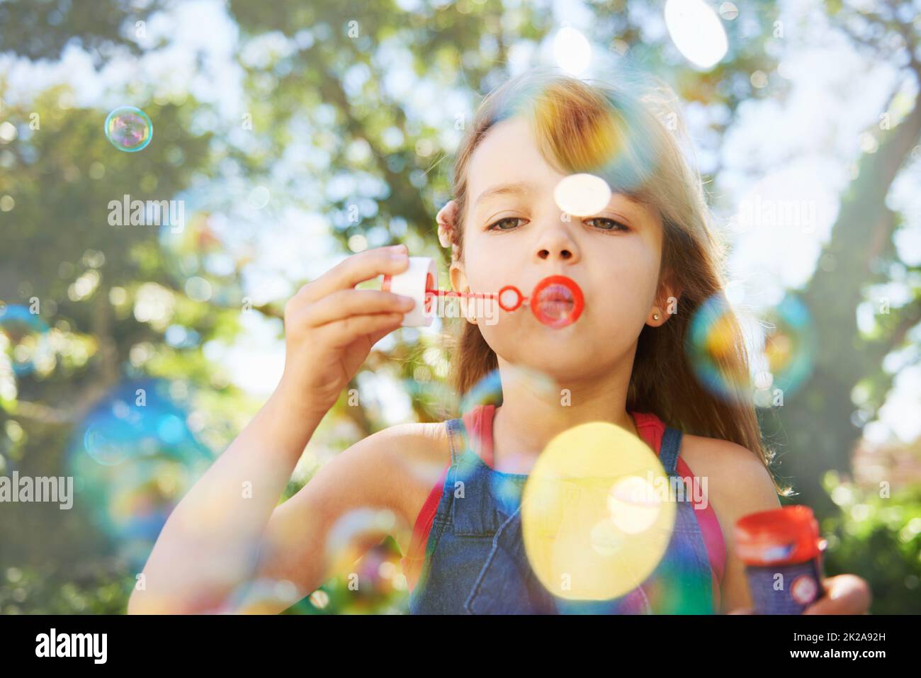 Bulles et vacances d'été. Photo d'une jeune fille mignonne soufflant des bulles à l'extérieur. Banque D'Images