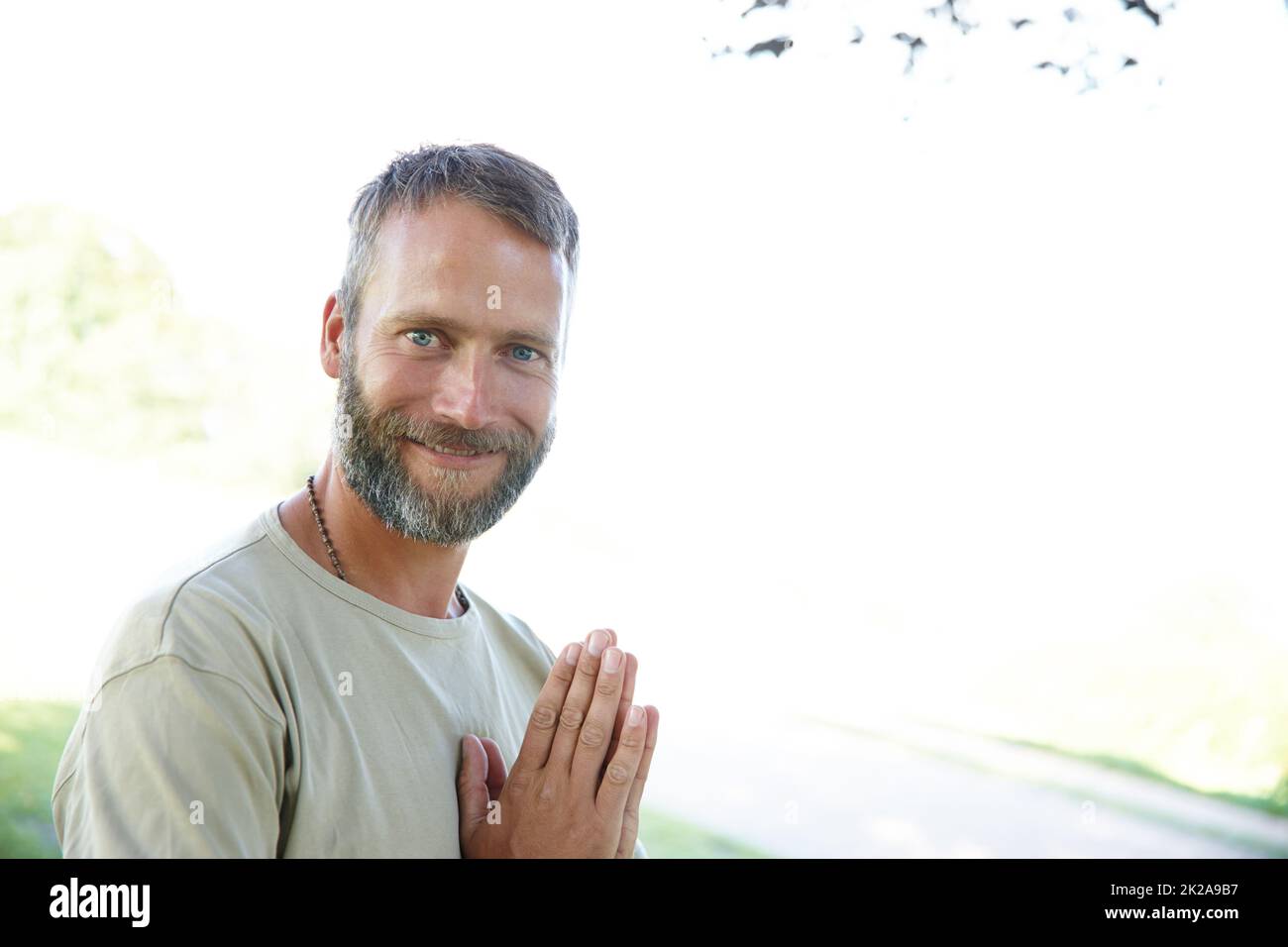 Namaste. Portrait d'un beau homme mature debout avec ses mains en position de prière à l'extérieur. Banque D'Images