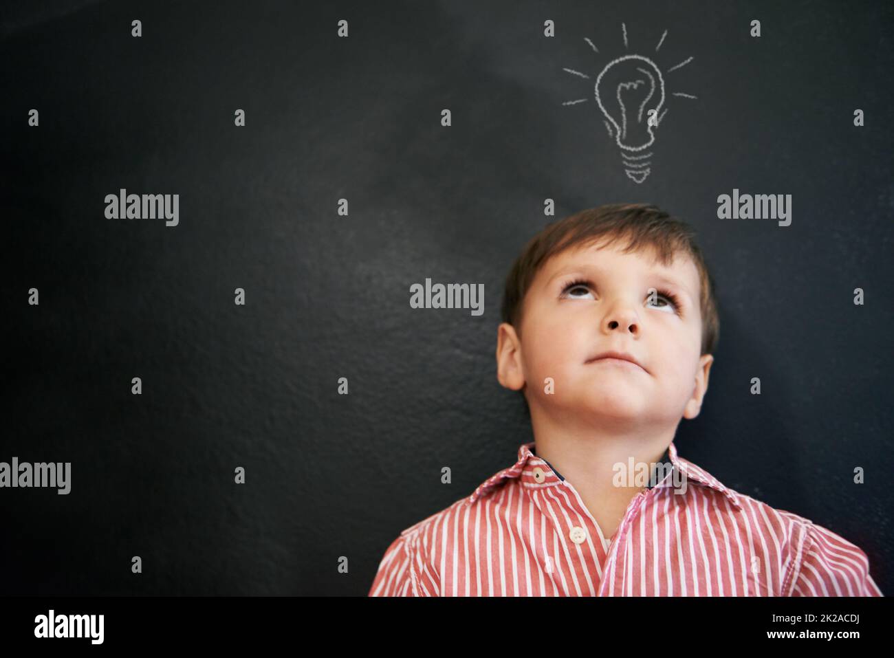 HES a eu beaucoup d'idées. Photo en studio d'un jeune garçon avec une ampoule à dessin de craie au-dessus de sa tête. Banque D'Images