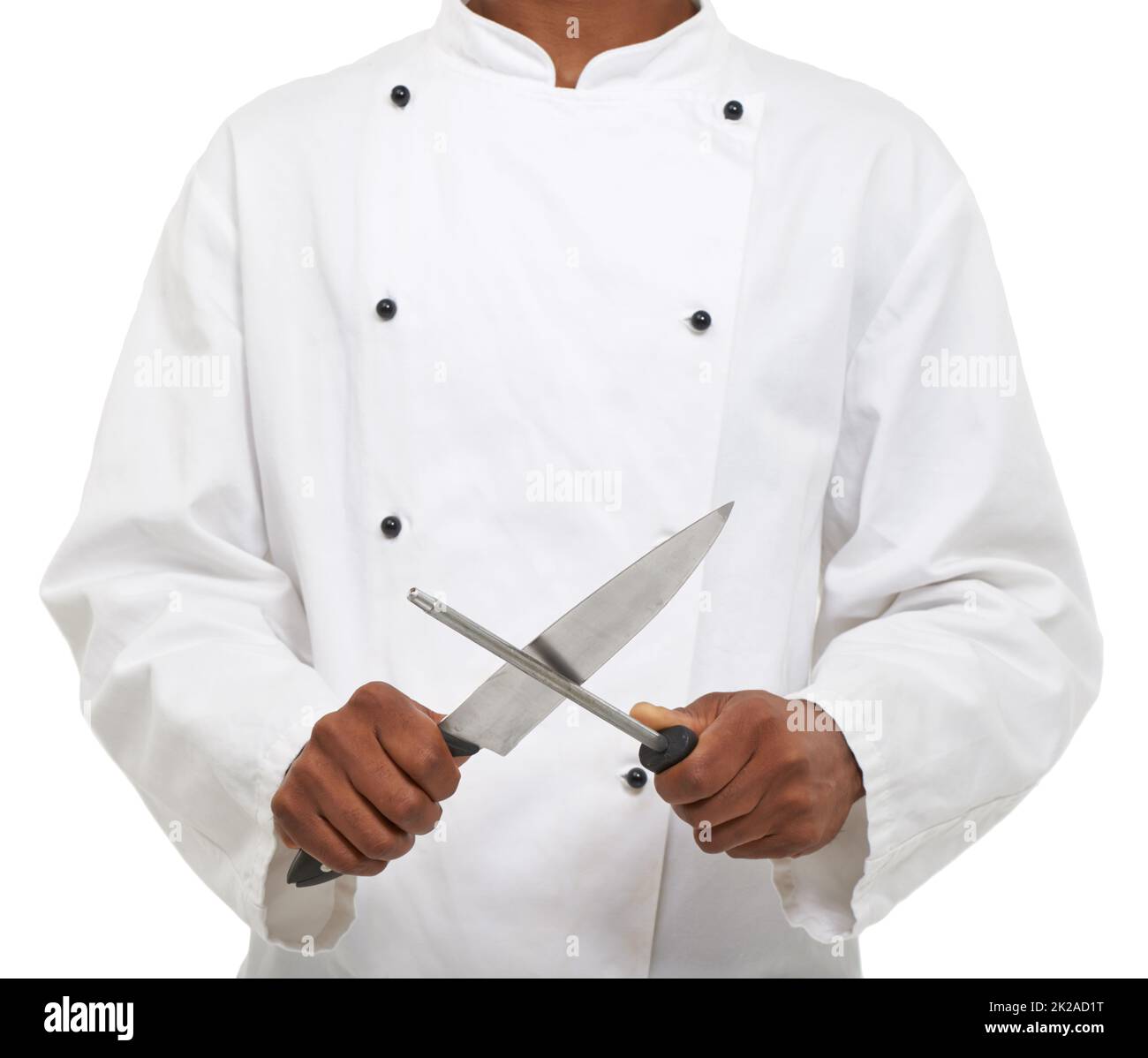 Outils du commerce. Un jeune chef aiguisant ses couteaux tout en étant isolé sur un fond blanc. Banque D'Images