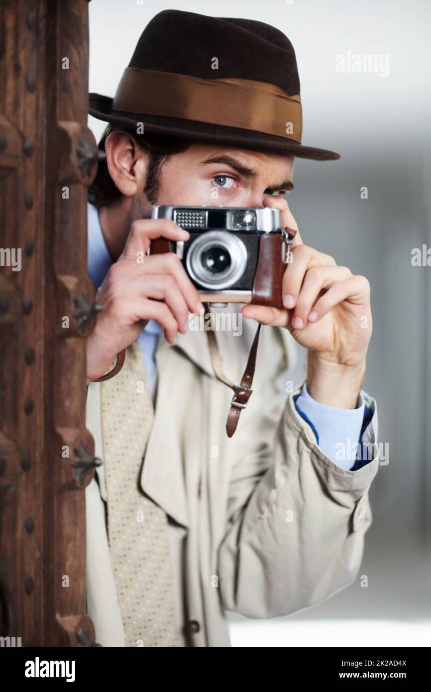 Capturer des activités illicites. Journaliste capturant une photo de manière suspecte depuis un coin de rue tout en utilisant un appareil photo rétro. Banque D'Images