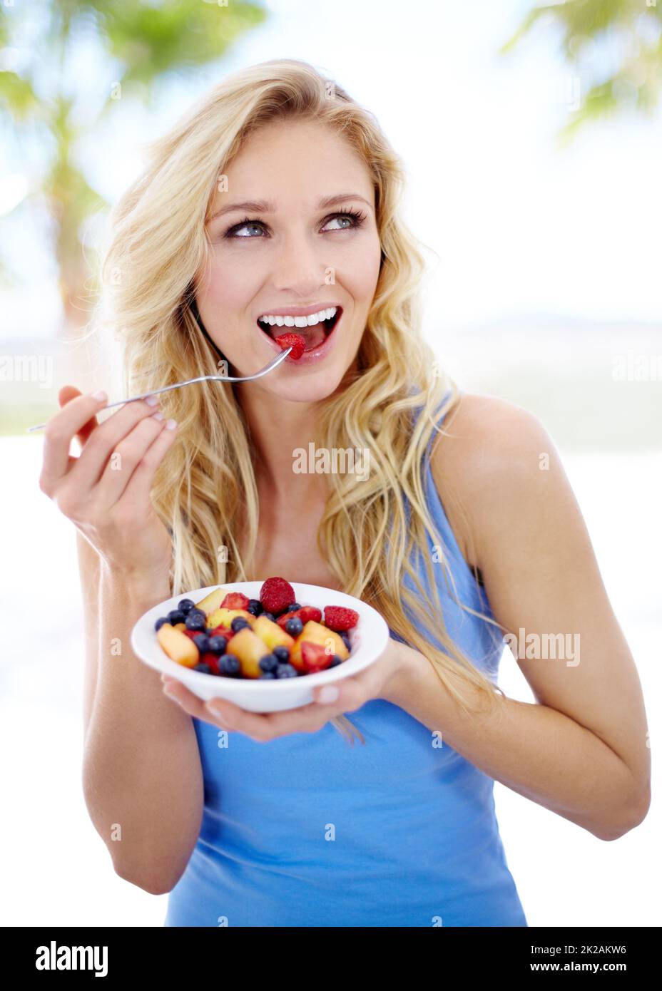 Un régime qu'elle peut apprécier. Jolie jeune femme appréciant sa salade de fruits. Banque D'Images