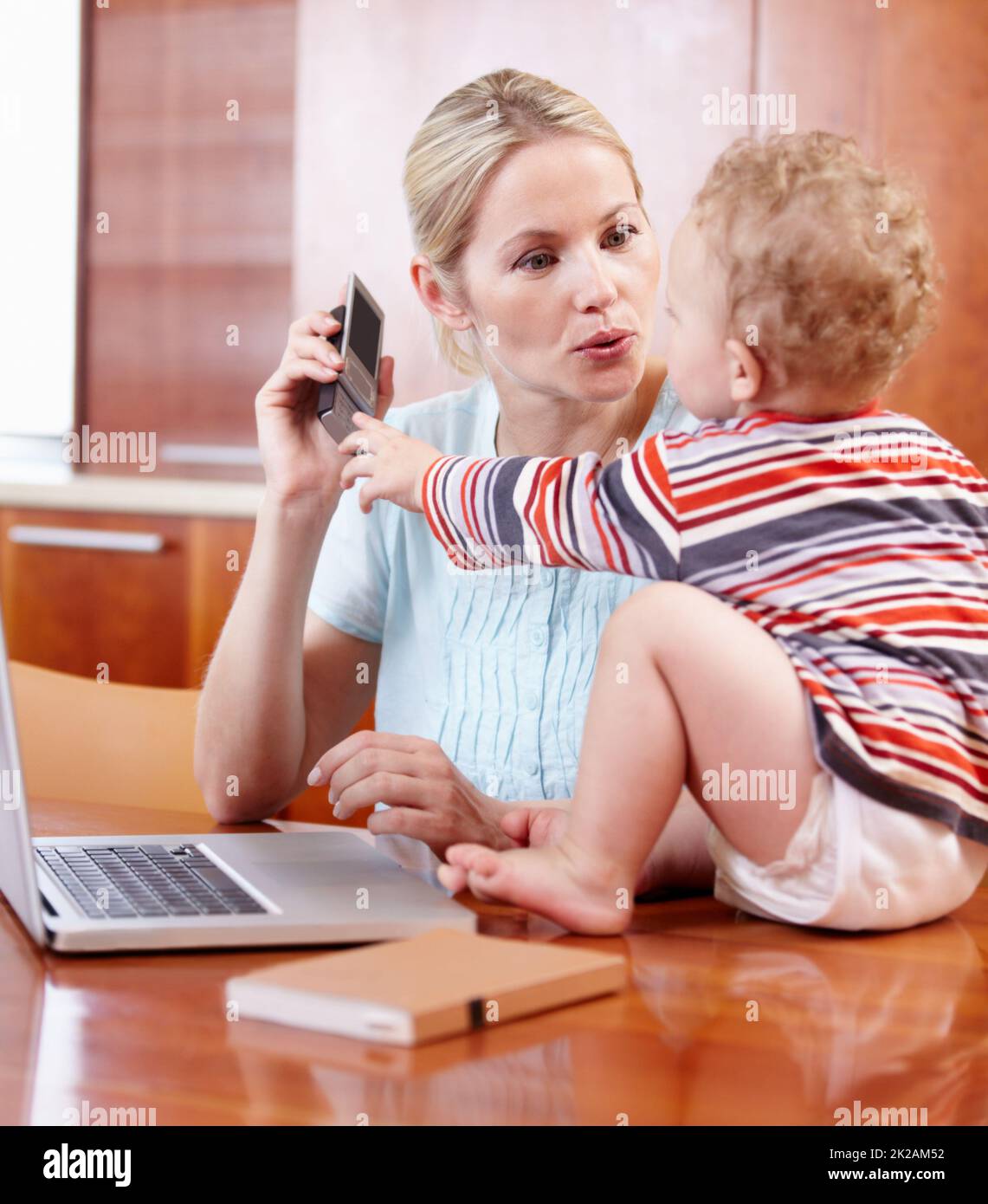 Curieux de la technologie. Une mère et son bébé jouant autour avec un téléphone portable et un ordinateur. Banque D'Images
