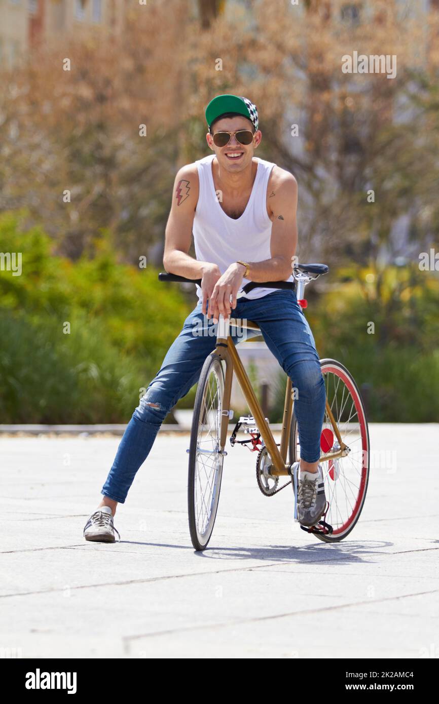 Style urbain sur roues. Un beau jeune homme à vélo en plein air. Banque D'Images