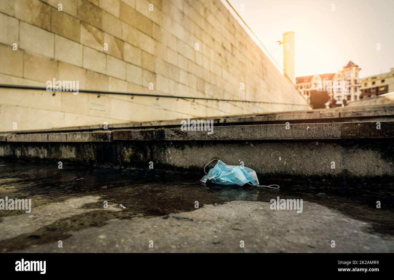 Masque médical utilisé jeter sur le sol sur le bâtiment flou dans la ville. Élimination des déchets médicaux sans hygiène. Ville sale. Masque facial poubelle sur le sol. Manque de responsabilité sociale. Mauvaise habitude. Banque D'Images