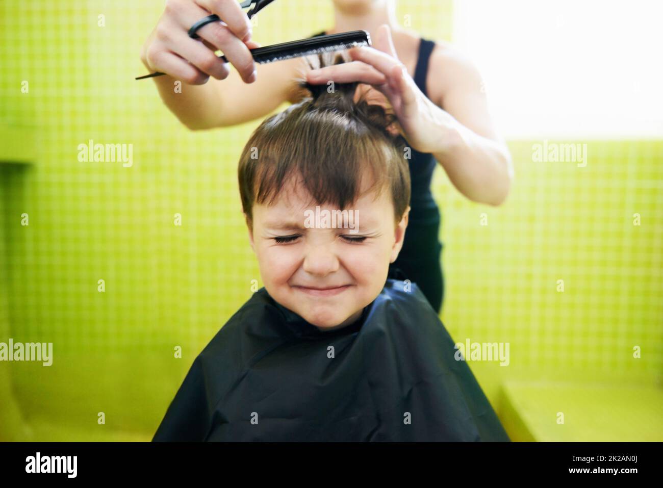 Sa première coupe de cheveux. Coupe courte d'un jeune garçon avec sa