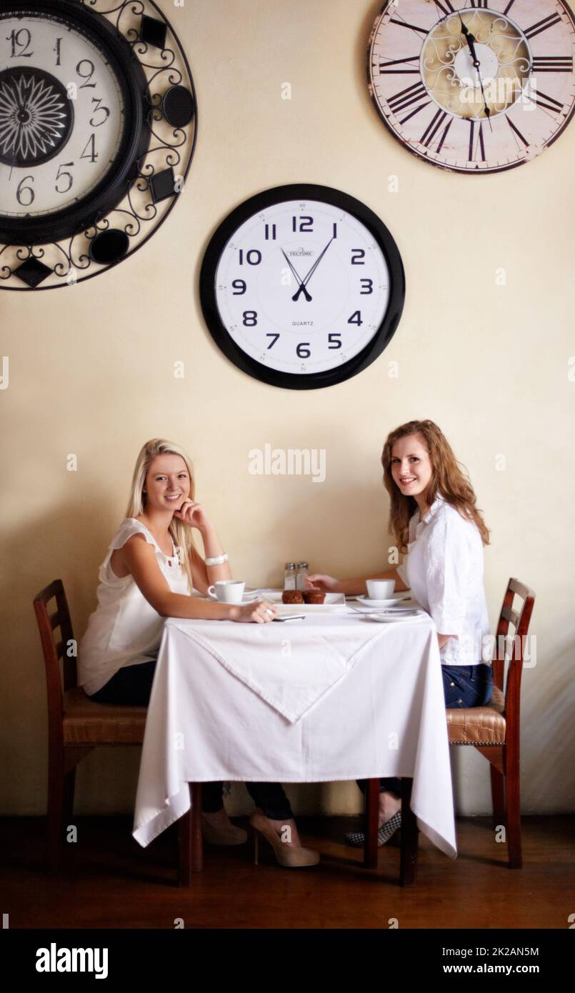 Il est temps de prendre du thé. Deux jeunes femmes souriantes qui apprécient le thé dans un café - portrait. Banque D'Images