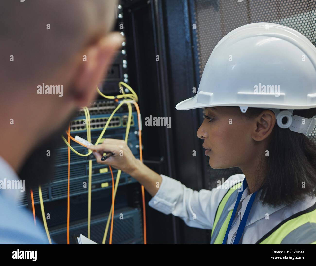 Il faut bien y parvenir. Prise de vue de deux employés qui inspectent ensemble l'équipement électronique dans une salle de serveurs au travail. Banque D'Images