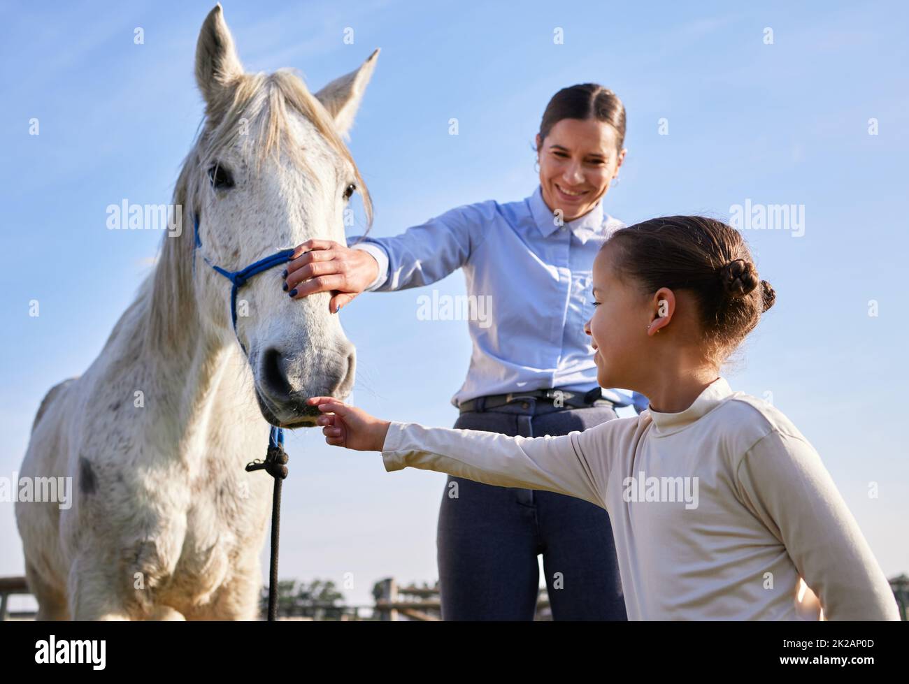 Comme ça. Coupe courte d'une jeune femme et de sa fille qui pillent un cheval à l'extérieur du ranch. Banque D'Images