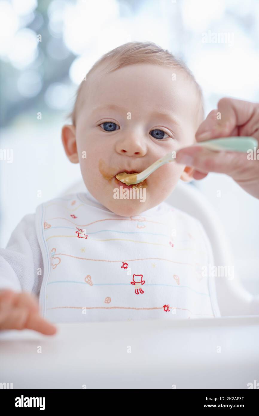 Désordonné et adorable. Image rognée d'un bébé garçon nourri par sa mère. Banque D'Images