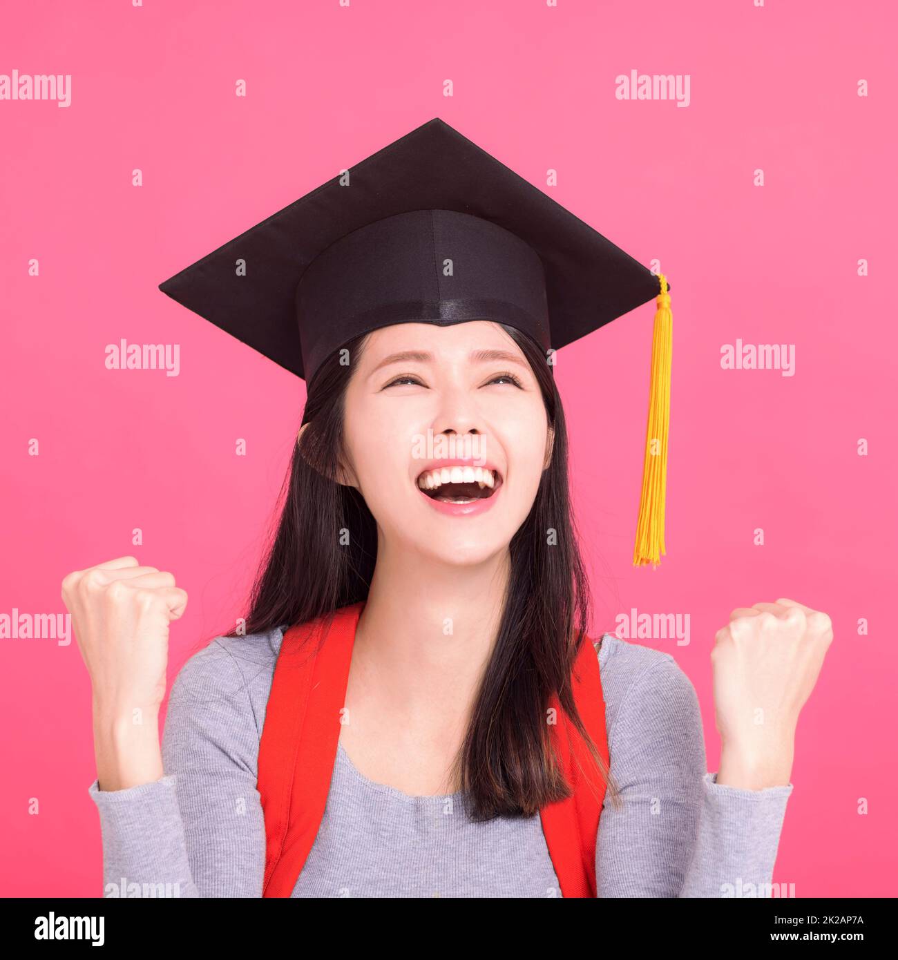 Joyeux étudiant asiatique dans la limite de remise des diplômes avec le geste de réussite Banque D'Images