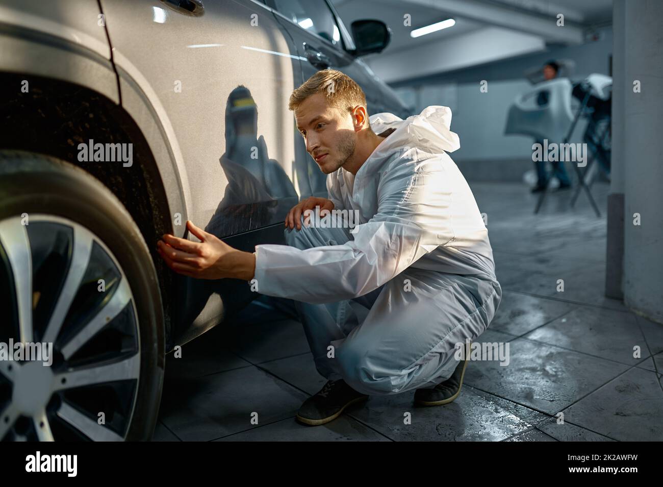 Peintre examinant le processus de vérification de la peinture de carrosserie de voiture Banque D'Images