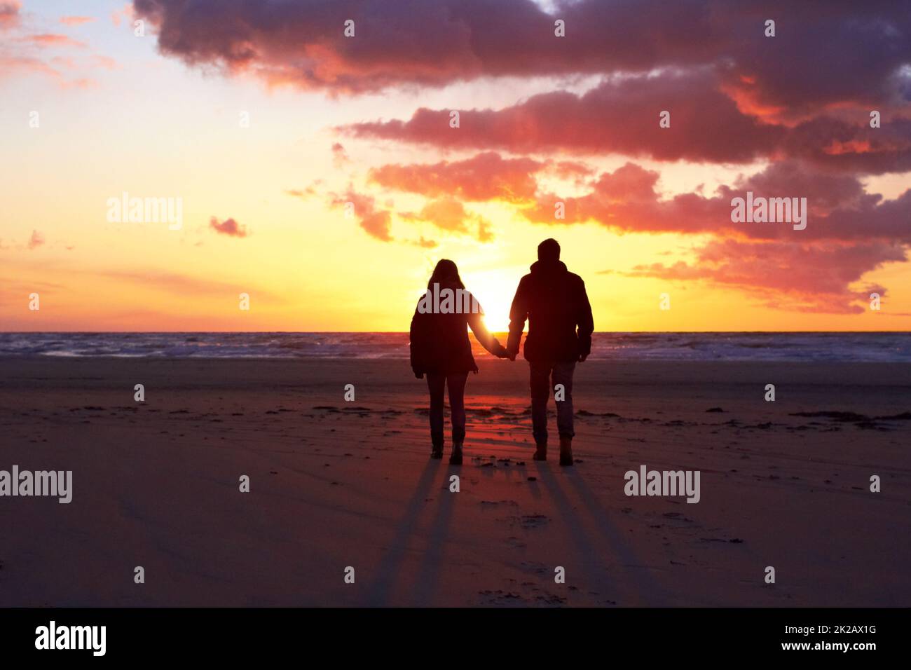 Ombres au coucher du soleil. Silhouette d'un couple qui va faire une promenade sur la plage au coucher du soleil. Banque D'Images