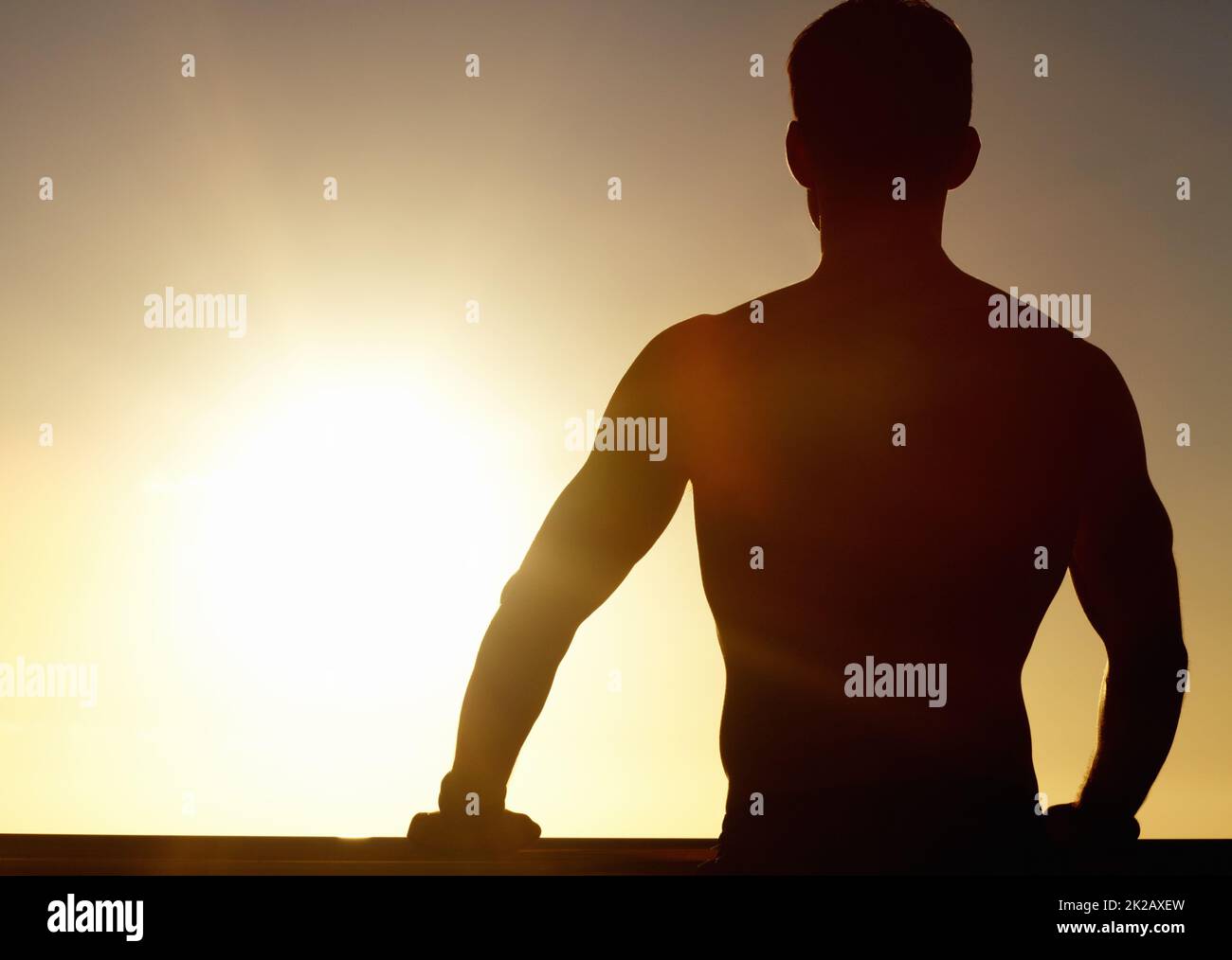 Face à un avenir radieux. Une silhouette d'un homme musclé regardant le coucher du soleil. Banque D'Images