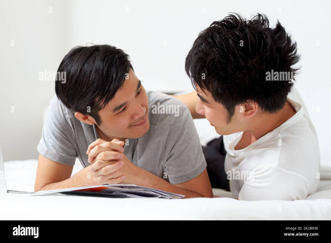 Vivre et aimer ensemble. Mignon jeune gay asiatique couple souriant tout en se relaxant à la maison ensemble. Banque D'Images