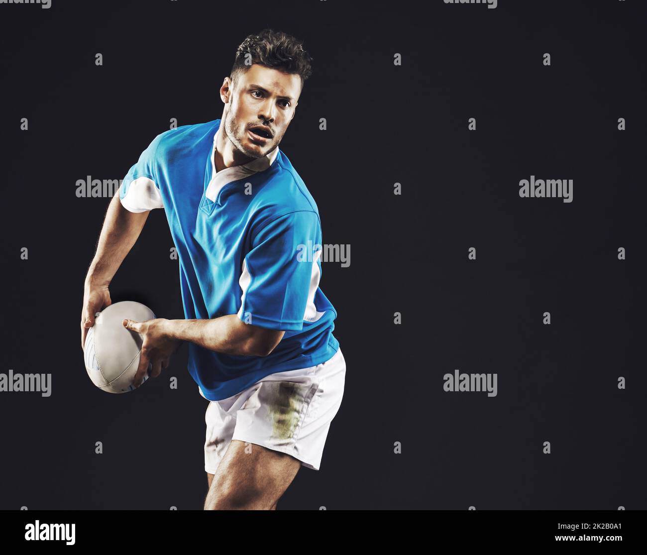 Il est temps d'essayer. Photo d'un joueur de rugby qui passe le ballon sur fond noir. Banque D'Images