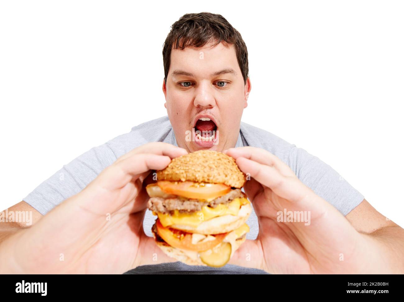 J'entre dans mon ventre, hamburger. Un jeune homme obèse sur le point de manger un énorme hamburger. Banque D'Images