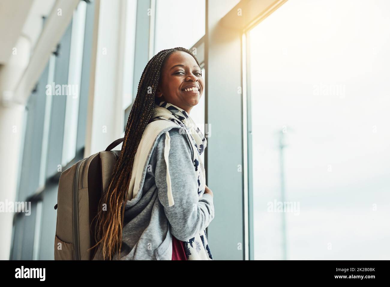 Ce sera ma première fois de vol. Photo courte d'une jeune femme regardant par la fenêtre de l'aéroport en attendant le départ. Banque D'Images