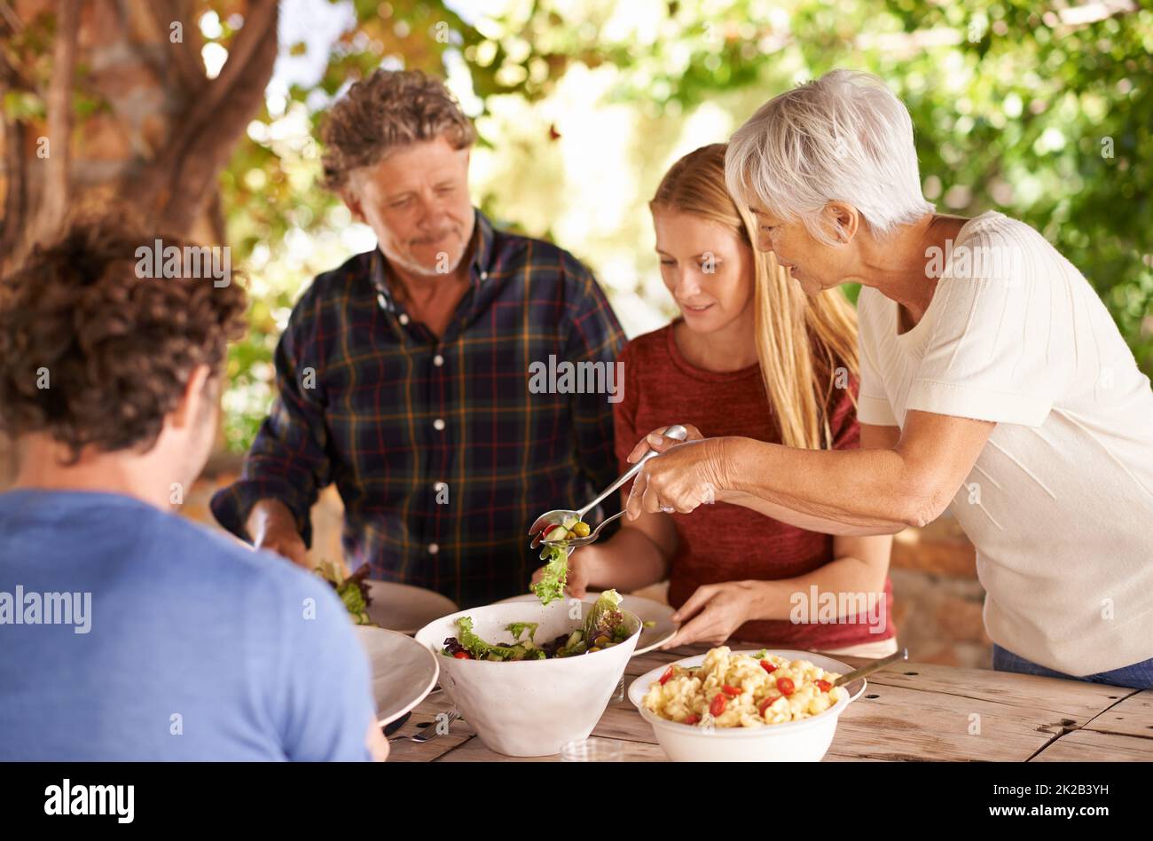 Voulez-vous un peu plus. Une vue d'une famille se préparant à manger le déjeuner ensemble à l'extérieur. Banque D'Images
