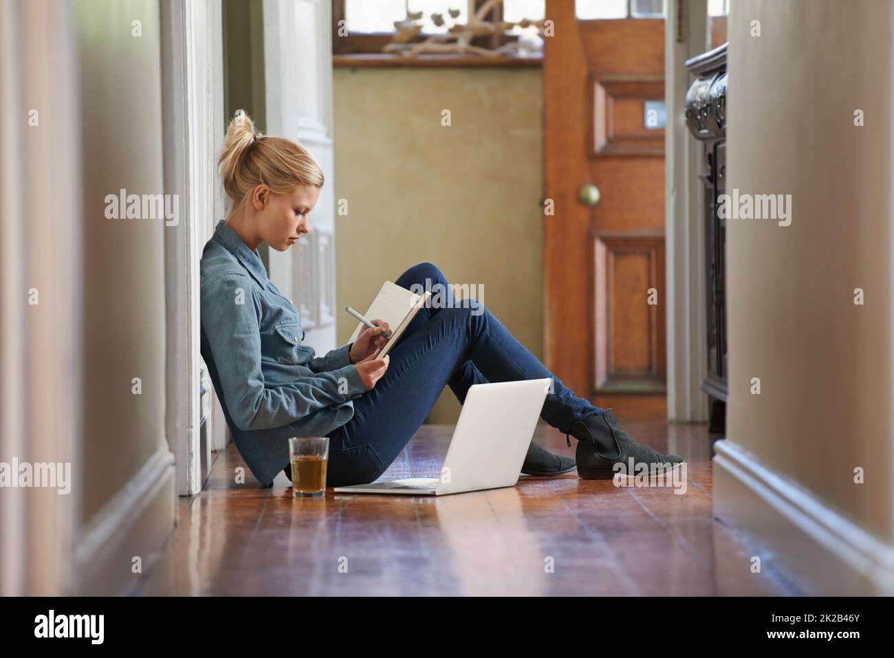 En vous privant de pensées. Une jeune femme assise sur le sol fait des recherches sur son ordinateur portable. Banque D'Images