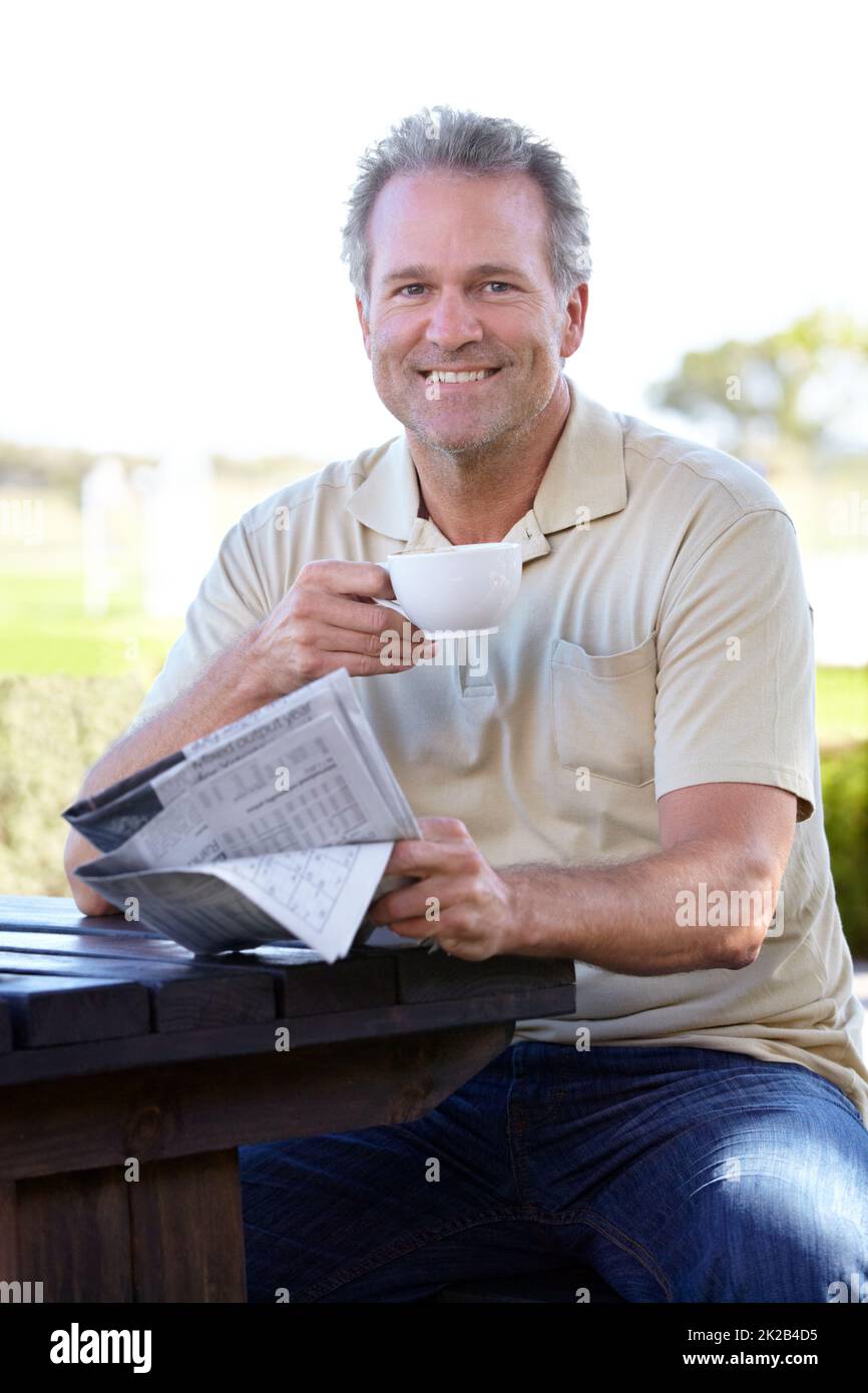 Pas de matinée complète sans café et un papier. Portrait d'un homme mature qui apprécie une tasse de café à l'extérieur tout en lisant un journal. Banque D'Images