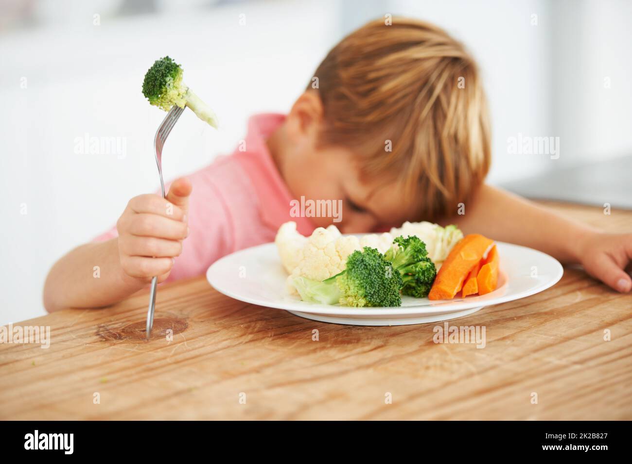Tout sauf le brocoli Un petit garçon très mécontent d'avoir à manger des légumes. Banque D'Images