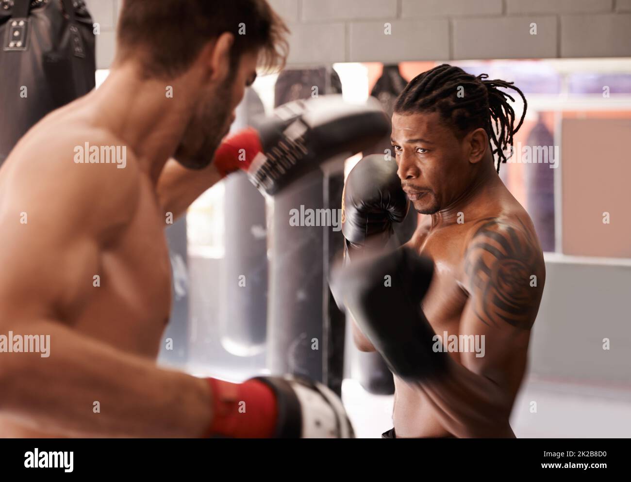 Des partenaires de boxe dédiés. Photo d'un jeune boxeur pratiquant sa perforation avec un partenaire. Banque D'Images