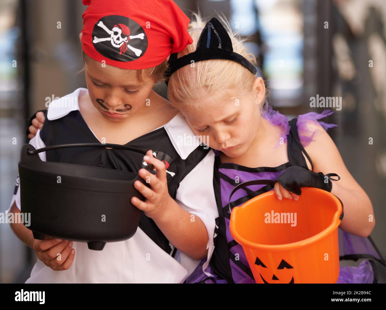 Déceptions infantiles. Un frère et une sœur se sultent ensemble et regardent leurs paniers vides doux à Halloween. Banque D'Images