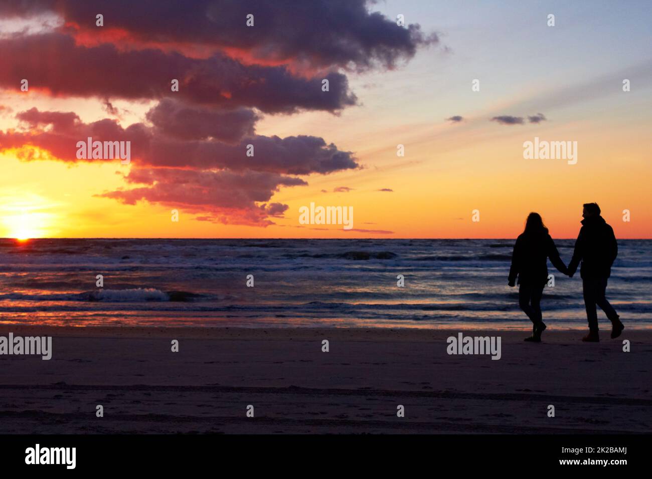 Theyve a trouvé leur paradis. Silhouette d'un couple qui va faire une promenade sur la plage au coucher du soleil. Banque D'Images