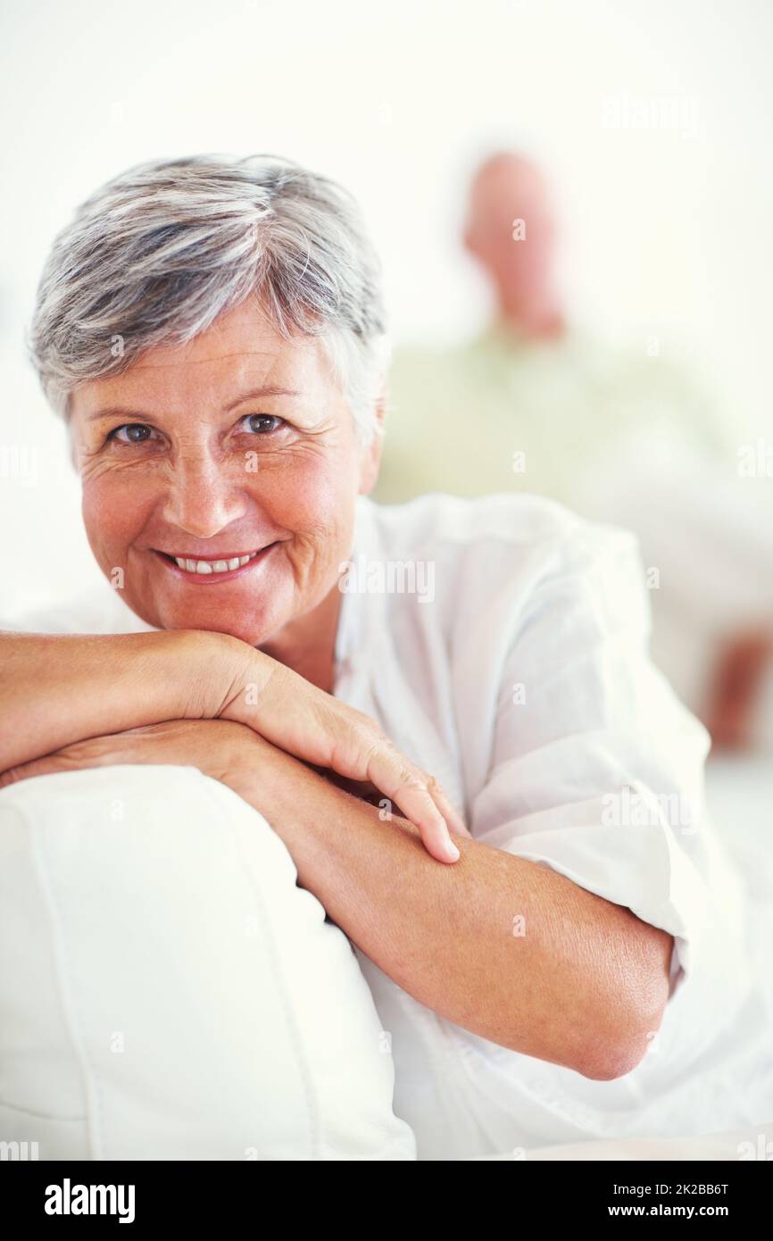 Belle femme mûre avec homme. Portrait d'une belle femme mûre souriant avec l'homme en arrière-plan à la maison. Banque D'Images