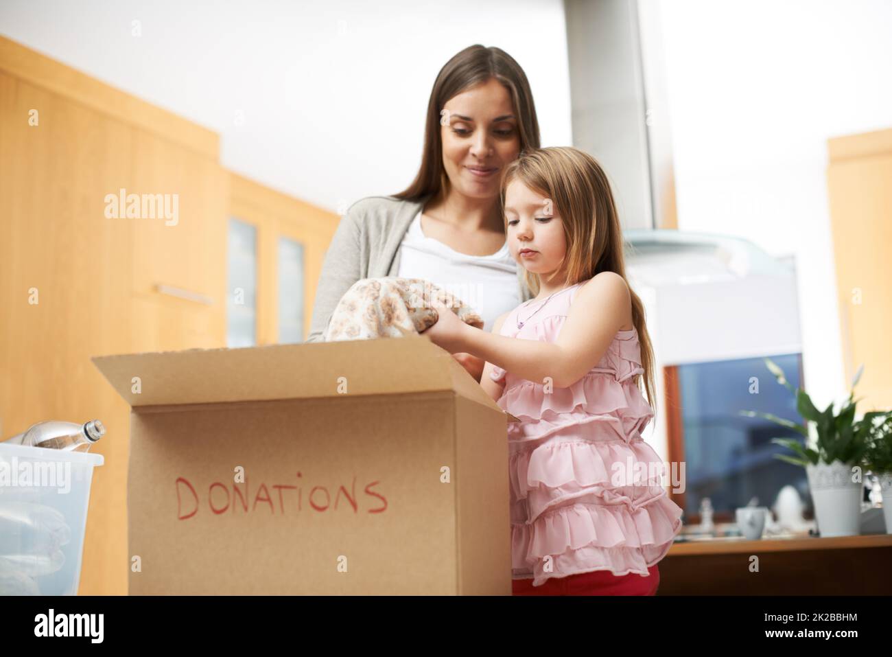 Mummys petit aide. Une jeune fille aidant sa mère avec un travail de charité. Banque D'Images