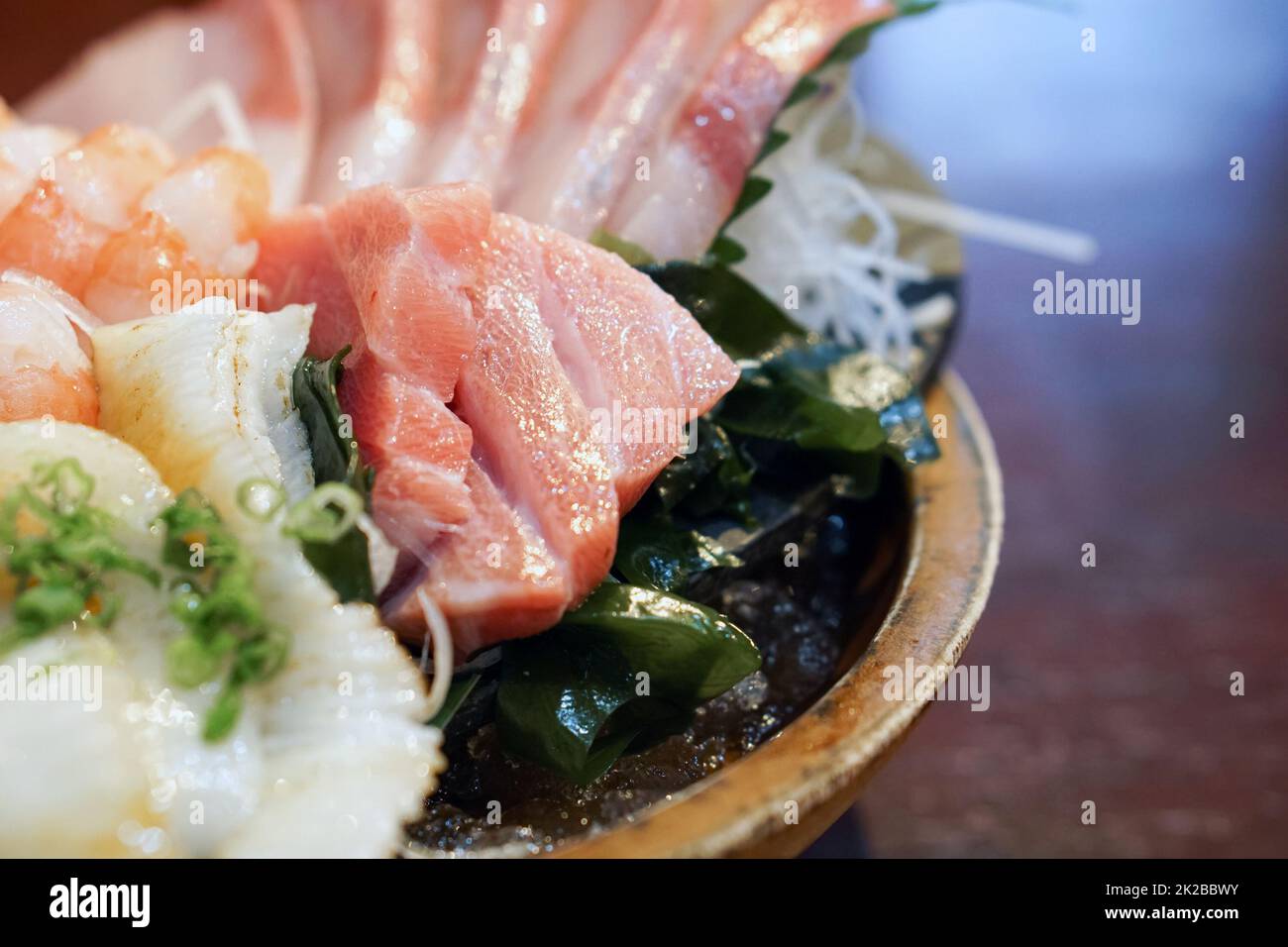 L'ensemble sashimi est magnifiquement disposé dans une assiette en bois. Buffet de cuisine japonaise. Choix du chef : thon, engawa, crevettes et hamachi Banque D'Images