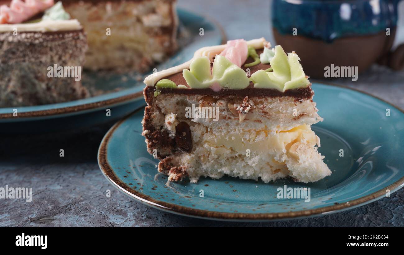 Morceau de gâteau de Kiev à la crème au chocolat et décoré sur une assiette bleue Banque D'Images